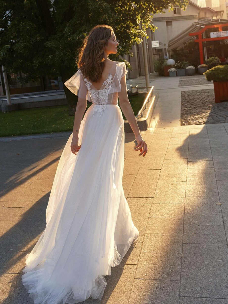 Cape sleeved wedding dress with illusion neckline and floral appliqué across the bodice