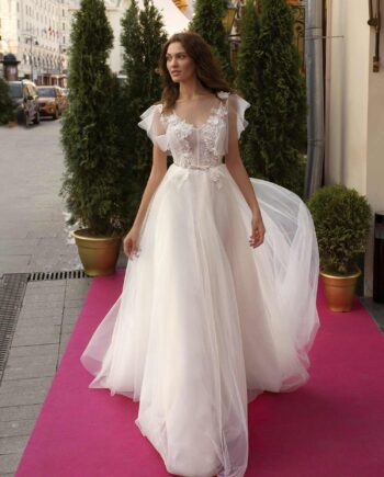 Cape sleeved wedding dress with illusion neckline and floral appliqué across the bodice