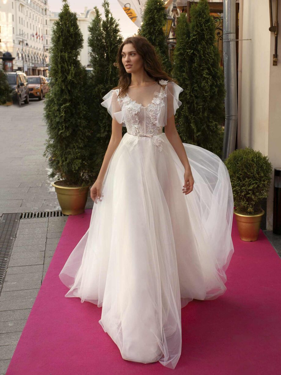 Cape sleeved wedding dress with illusion neckline and floral appliqué across the bodice