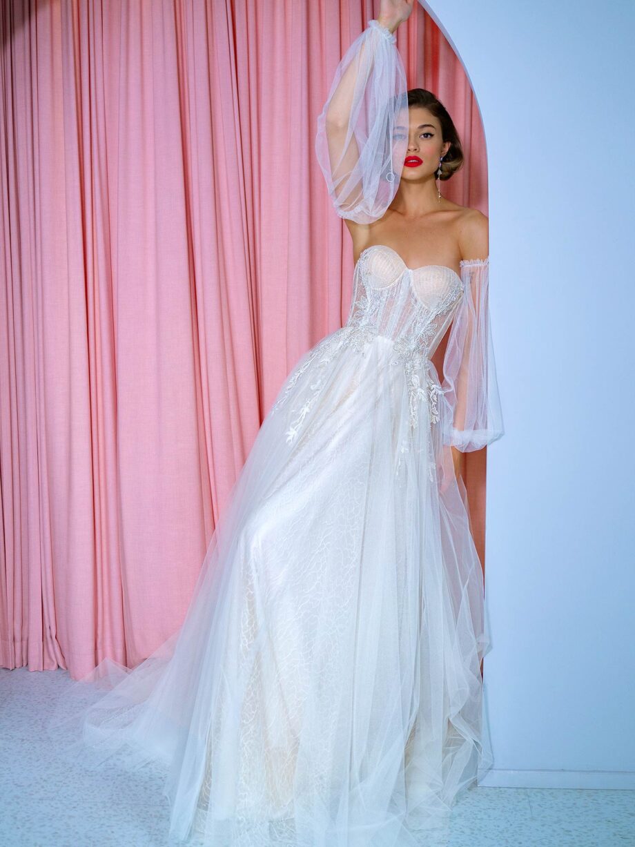 Front view of an A-line wedding dress with detachable puff sleeves, featuring a corset bodice and embroidered details. Dress by Papilio Boutique bridal store in Toronto.