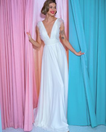 Front view of a sheath wedding gown with beaded fringe sleeves, featuring a deep V neckline and flowing chiffon skirt, available at Papilio Boutique bridal store in Toronto.