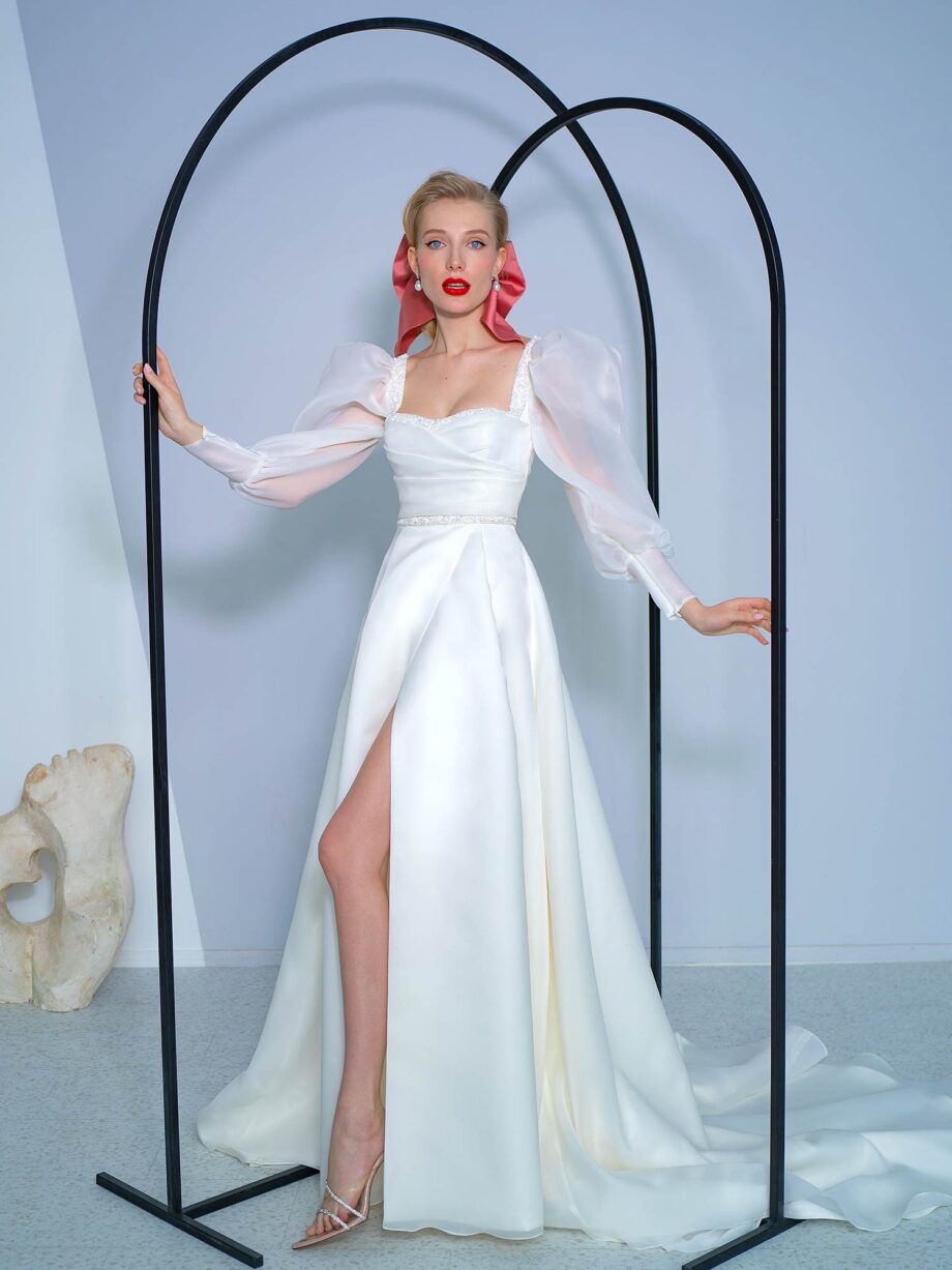 Elegant A-line wedding dress with bishop sleeves and a high slit, made from airy organza fabric, available at Papilio Boutique in Toronto.