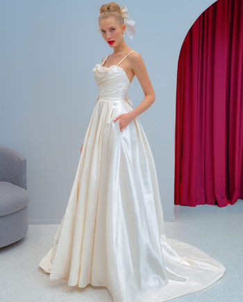 A full-length view of a satin ball gown with floral appliqués and a luxurious flowing train at Papilio Boutique.