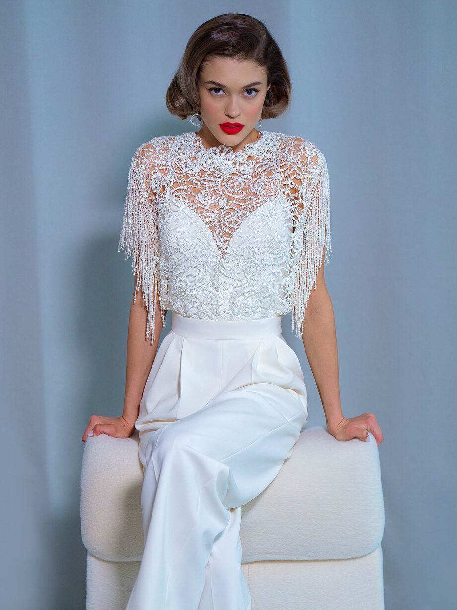 A modern bridal jumpsuit with a lace top and beaded fringe, featuring a high neckline and tailored crepe pants, available at Papilio Boutique in Toronto.