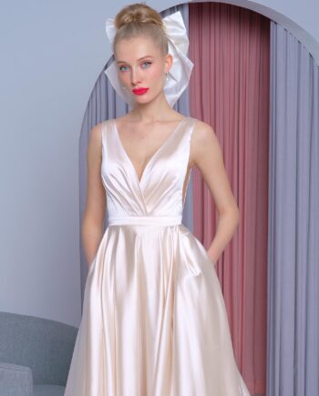 Satin A-line wedding dress in gold with a deep V-neckline, flowing train, and hidden pockets, available at Papilio Boutique in Toronto.