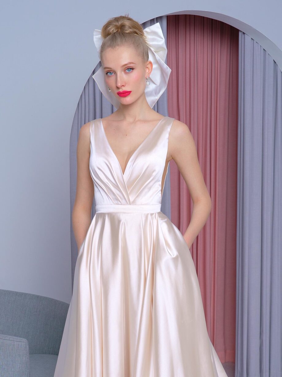 Satin A-line wedding dress in gold with a deep V-neckline, flowing train, and hidden pockets, available at Papilio Boutique in Toronto.