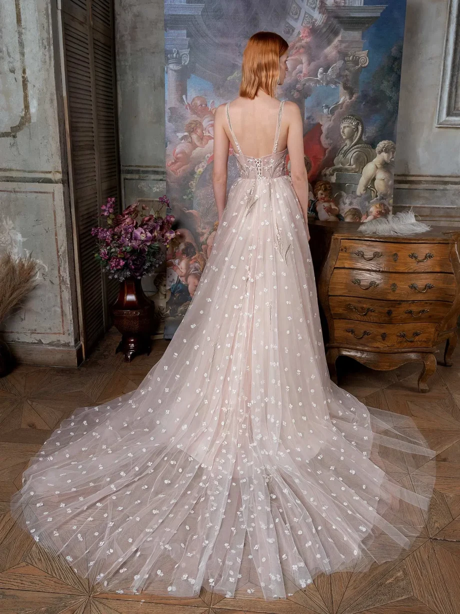 Back view of a bride in a pink-ivory ballgown showcasing the delicate lace-up back of the semi-sheer corset and the expansive floral tulle train, available in the Papilio Boutique sample sale in Toronto, set in a richly decorated vintage setting.