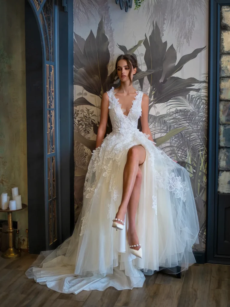 Bride in a floral lace wedding dress with a deep V-neckline, seated in a stylish setting at Papilio Boutique, a designer bridal store in Toronto.