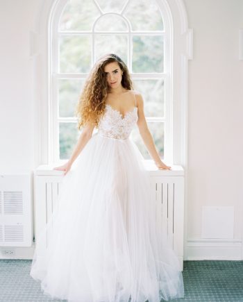 Front view of a simple ballgown wedding dress with lace bustier corset, spaghetti straps, and full ivory tulle skirt over nude lining, available at Papilio Boutique's sample sale in Toronto