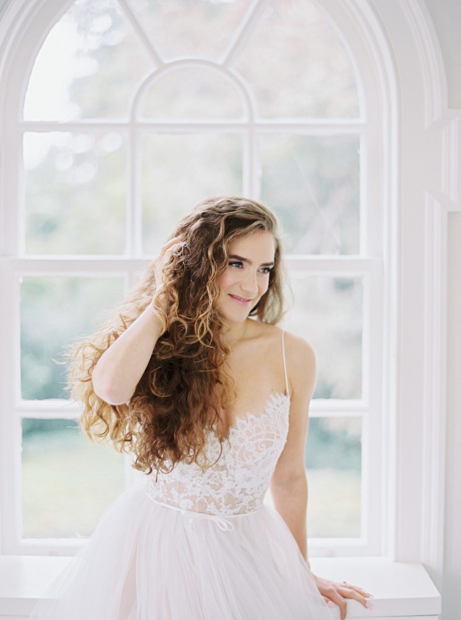 Front view of a simple ballgown wedding dress with lace bustier corset, spaghetti straps, and full ivory tulle skirt over nude lining, available at Papilio Boutique's sample sale in Toronto