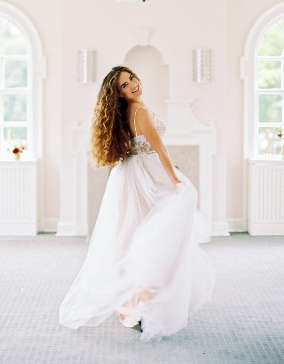 Back view of a simple ballgown wedding dress featuring a lace-up corset back, spaghetti straps, and a full ivory tulle skirt, showcased at Papilio Boutique's sample sale in Toronto.