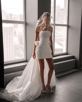bride wearing short strapless wedding dress with detachable train in studio setting, available at bridal stores in Toronto and Toronto bridal shop
