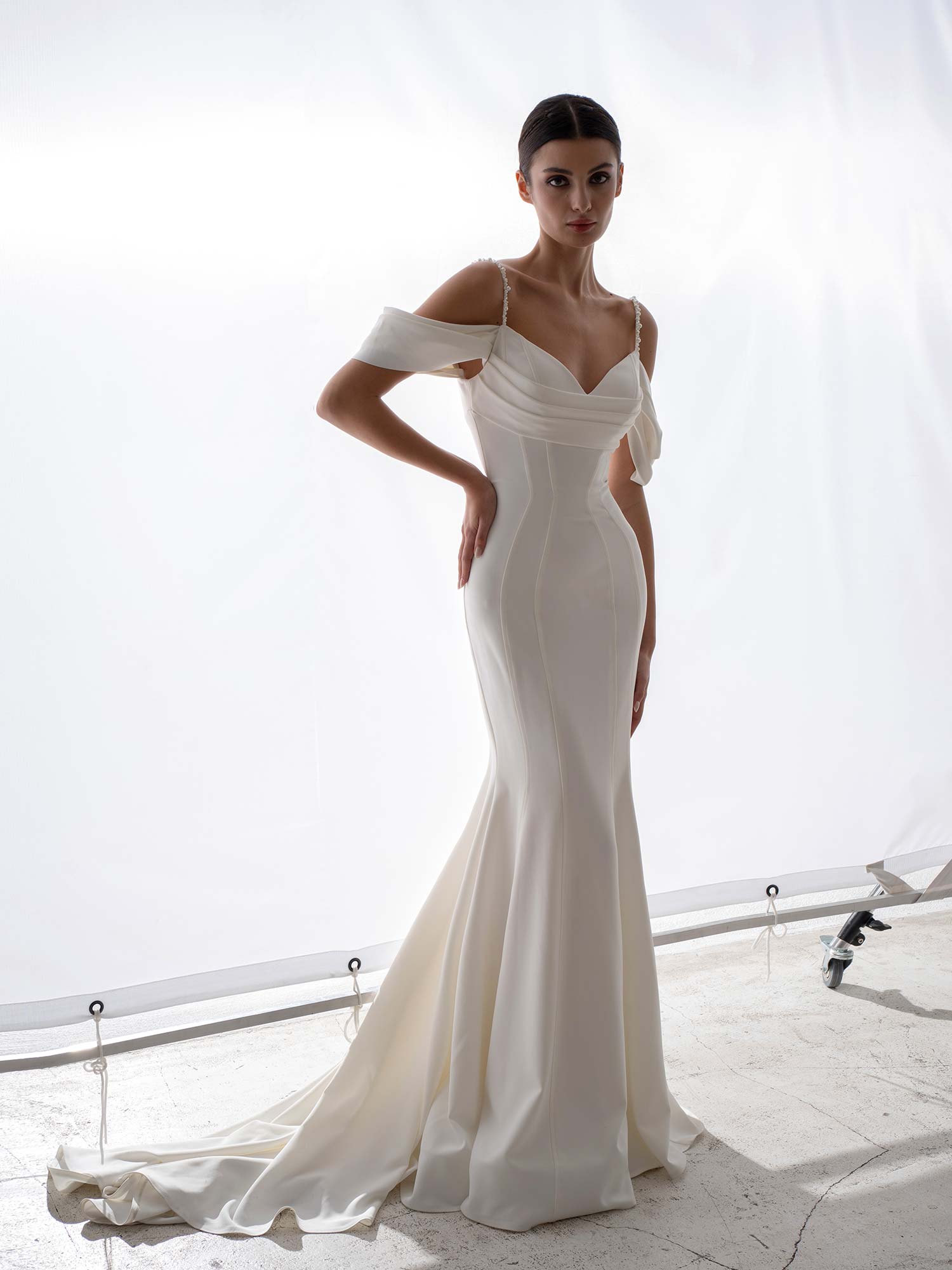Simple wedding dress with off the shoulder straps and draped bodice by Papilio Boutique, bridal store in Toronto.