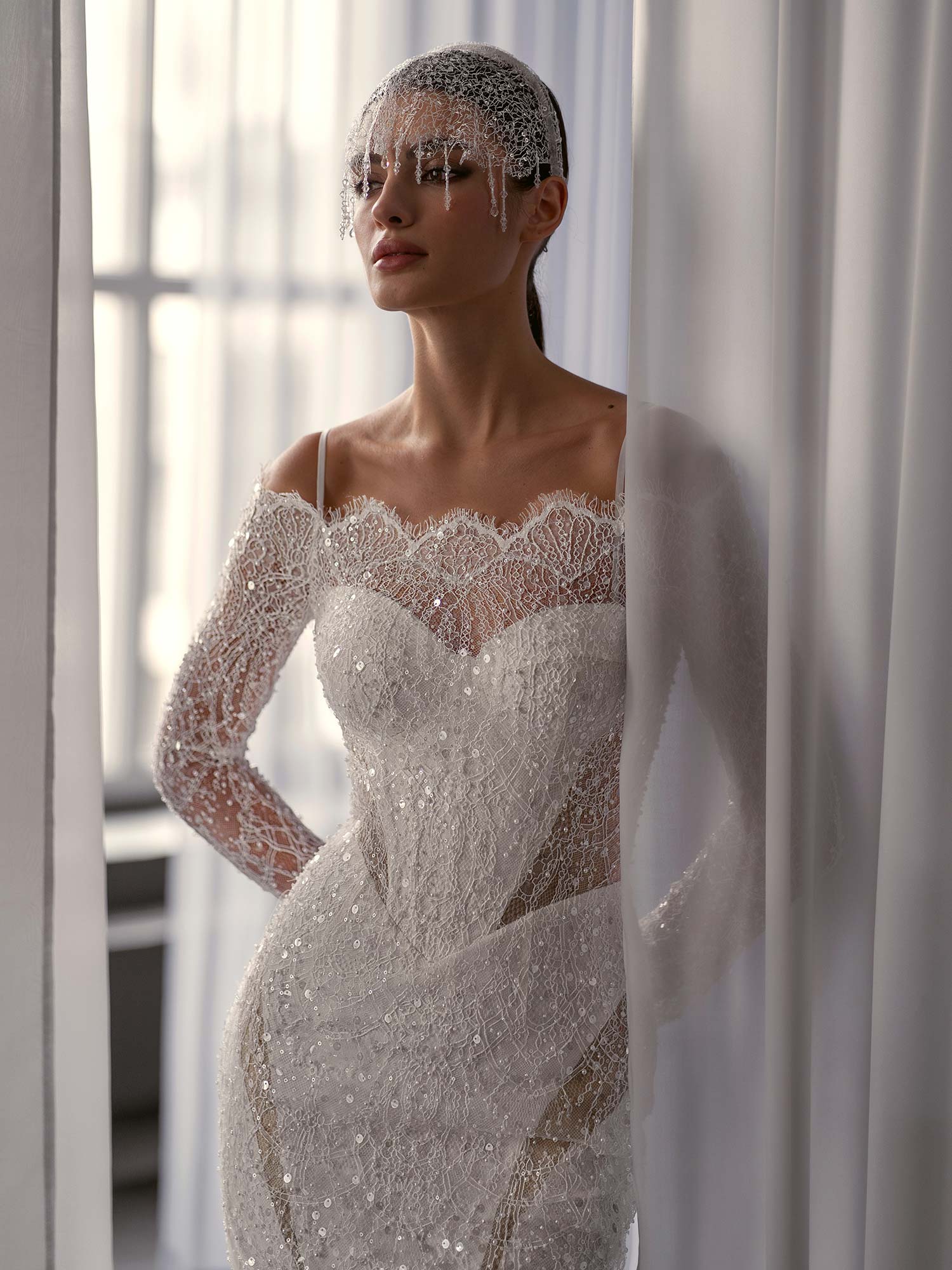 Close-up of shimmering off the shoulder wedding dress with long sleeves by Papilio Boutique, featuring intricate beading and lace details, from a Toronto bridal shop.